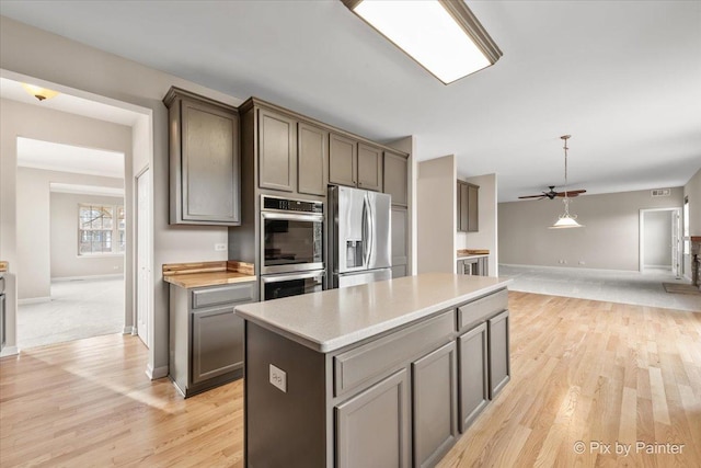 kitchen featuring stainless steel appliances, ceiling fan, light hardwood / wood-style flooring, a center island, and gray cabinets