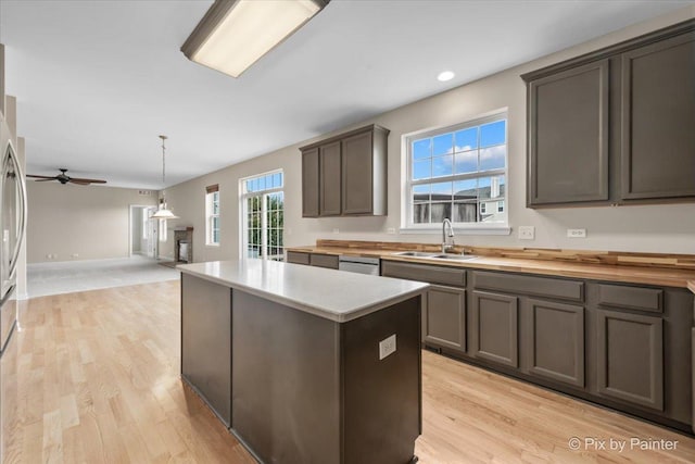 kitchen with stainless steel dishwasher, ceiling fan, sink, light hardwood / wood-style flooring, and a center island