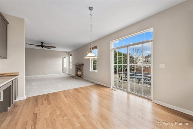 unfurnished living room with light wood-type flooring and ceiling fan