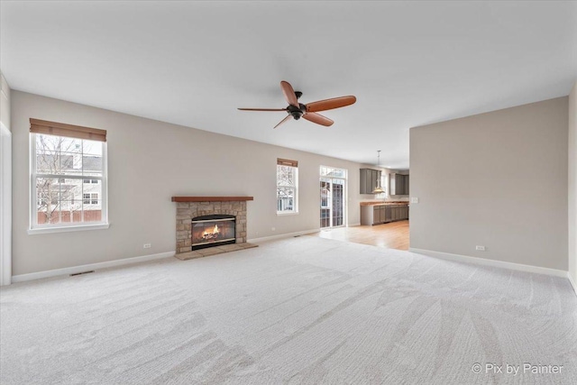 unfurnished living room featuring a fireplace, light colored carpet, and ceiling fan