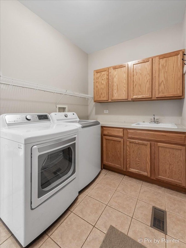 clothes washing area featuring cabinets, light tile patterned floors, separate washer and dryer, and sink