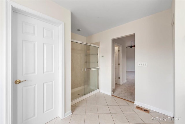 bathroom with tile patterned flooring, ceiling fan, and a shower with shower door