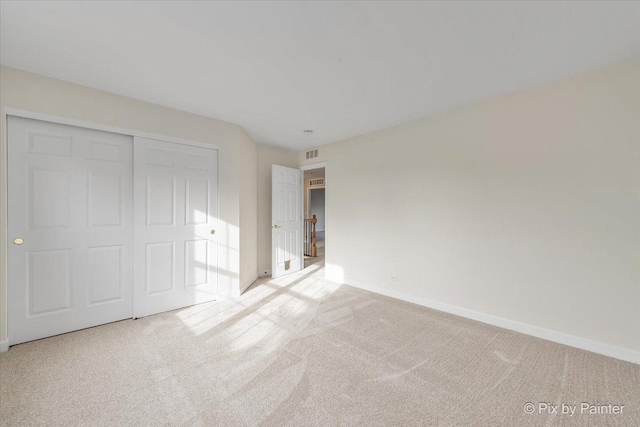 unfurnished bedroom featuring light colored carpet and a closet