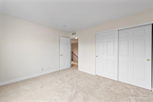 unfurnished bedroom featuring a closet and light colored carpet