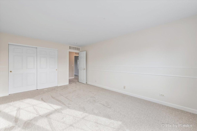 unfurnished bedroom featuring light carpet and a closet