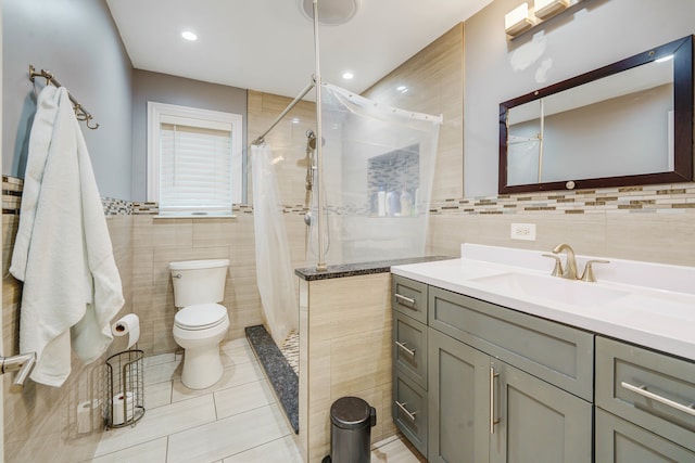 bathroom with toilet, tile patterned floors, vanity, curtained shower, and tile walls