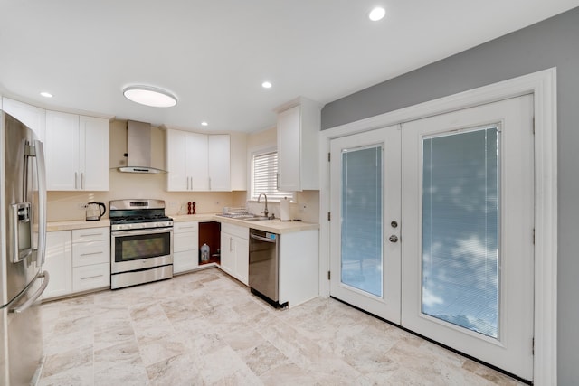 kitchen with white cabinetry, stainless steel appliances, french doors, sink, and wall chimney exhaust hood