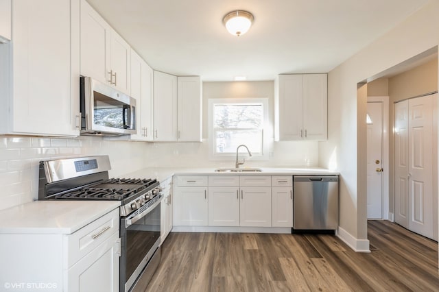 kitchen featuring wood-type flooring, sink, appliances with stainless steel finishes, and white cabinetry