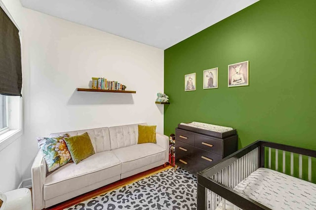 bedroom with a nursery area and wood-type flooring