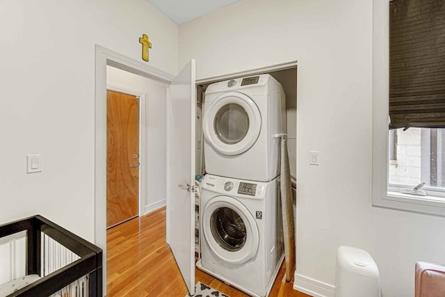 laundry area with stacked washer and clothes dryer and light hardwood / wood-style floors