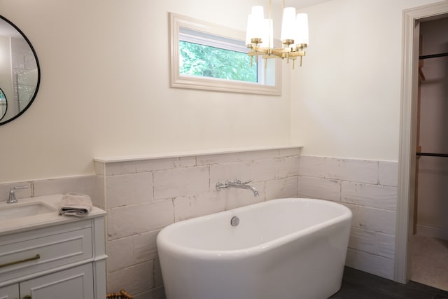 bathroom featuring a tub, tile walls, an inviting chandelier, and vanity