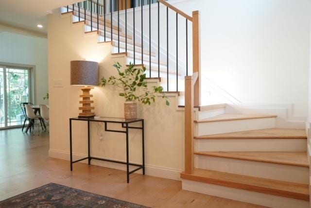 staircase featuring recessed lighting, baseboards, a high ceiling, and wood finished floors