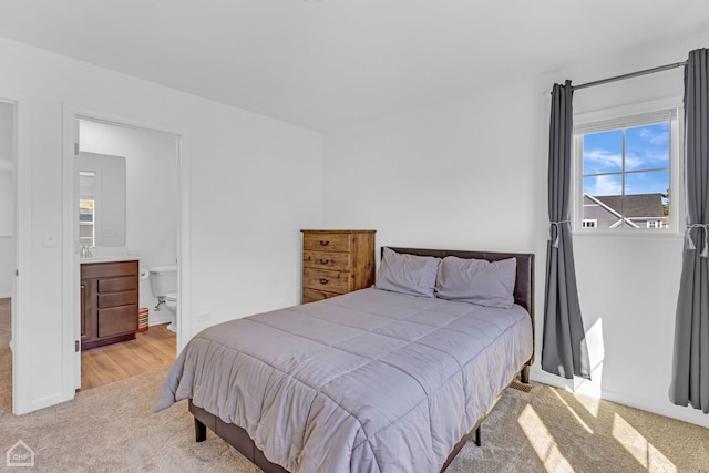 bedroom with ensuite bath and light carpet