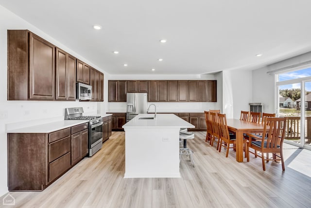 kitchen featuring light wood-type flooring, sink, appliances with stainless steel finishes, and a kitchen island with sink