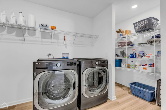 washroom with washing machine and clothes dryer and light hardwood / wood-style flooring