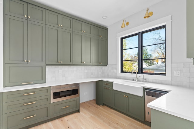 kitchen with light wood-type flooring, green cabinets, stainless steel appliances, and sink