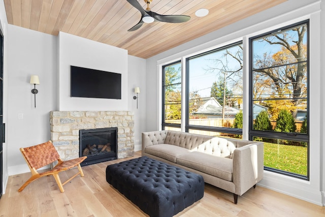 living room featuring wood ceiling, light hardwood / wood-style flooring, ceiling fan, and a fireplace