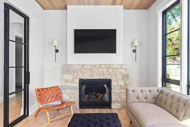 interior space featuring wood ceiling, a stone fireplace, and light wood-type flooring