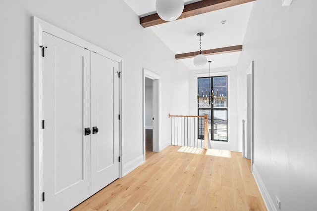 hallway featuring light wood-type flooring and vaulted ceiling with beams