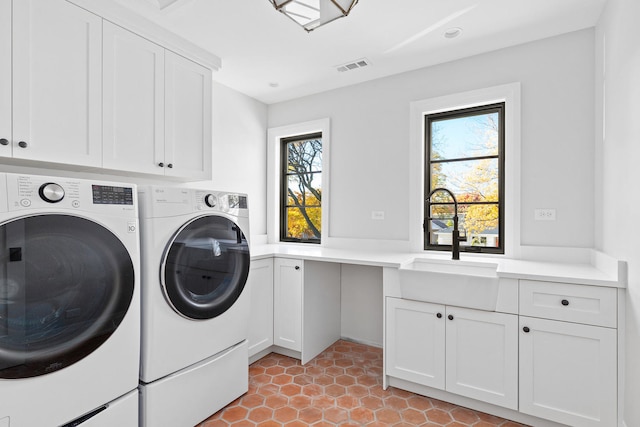 laundry area featuring separate washer and dryer, a healthy amount of sunlight, cabinets, and sink