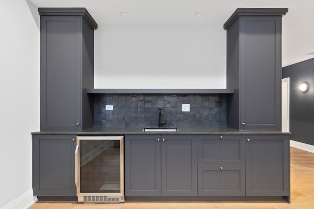 interior space featuring backsplash, gray cabinetry, light hardwood / wood-style floors, sink, and beverage cooler