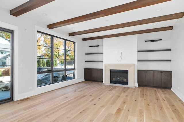 unfurnished living room featuring built in shelves, a fireplace, beam ceiling, and light hardwood / wood-style flooring