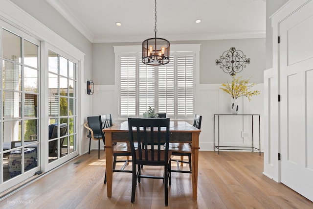 dining space with ornamental molding, a healthy amount of sunlight, an inviting chandelier, and light hardwood / wood-style floors