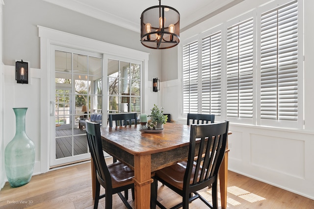 dining room with light wood-type flooring, an inviting chandelier, and ornamental molding