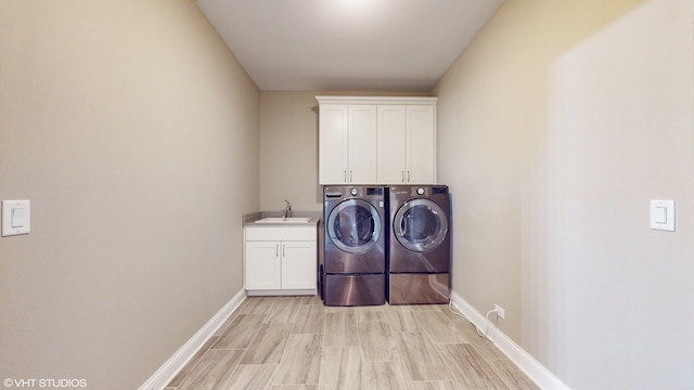 washroom featuring independent washer and dryer, cabinets, sink, and light hardwood / wood-style floors