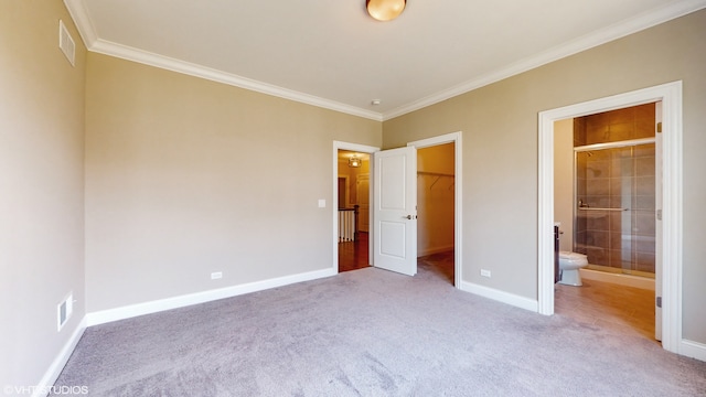 unfurnished bedroom featuring a walk in closet, a closet, light carpet, ensuite bathroom, and ornamental molding