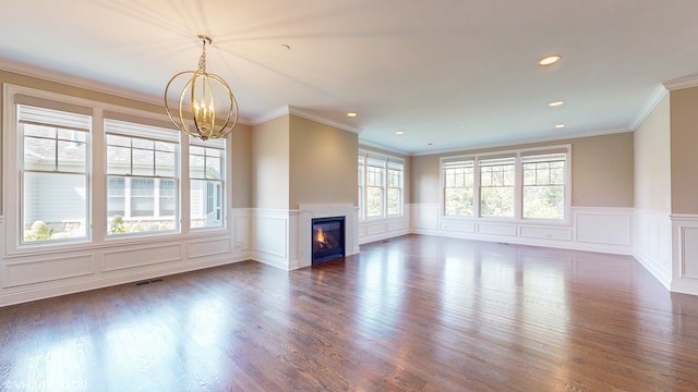 unfurnished living room with a wealth of natural light, dark hardwood / wood-style flooring, crown molding, and a premium fireplace