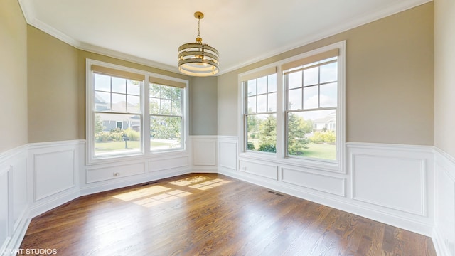 spare room with ornamental molding, dark wood-type flooring, a wealth of natural light, and a chandelier