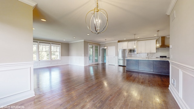 kitchen featuring wall chimney range hood, appliances with stainless steel finishes, hardwood / wood-style flooring, and tasteful backsplash