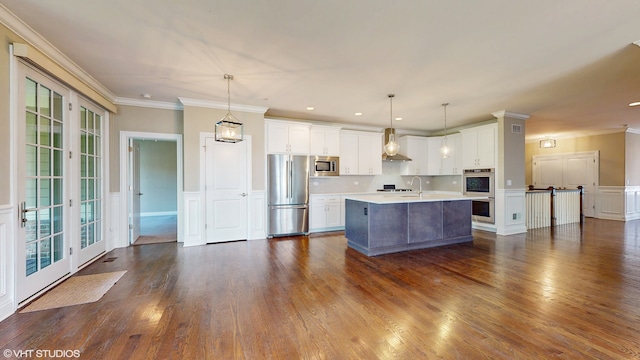 kitchen featuring dark hardwood / wood-style flooring, appliances with stainless steel finishes, wall chimney exhaust hood, and an island with sink