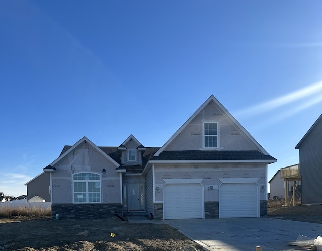 view of front of house featuring driveway, stone siding, a garage, and roof with shingles