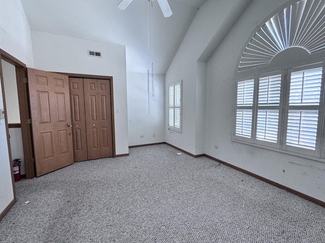 unfurnished bedroom featuring light carpet, a closet, multiple windows, and ceiling fan