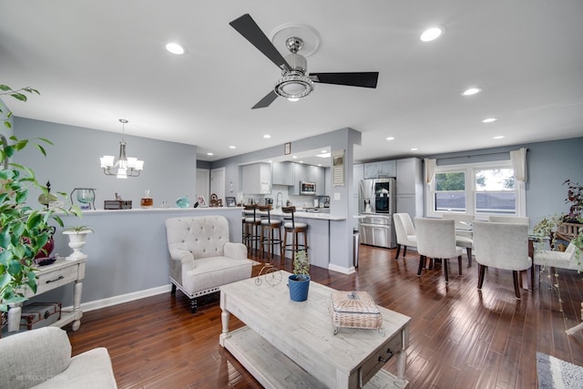 living room with dark wood-type flooring, ceiling fan with notable chandelier, and sink