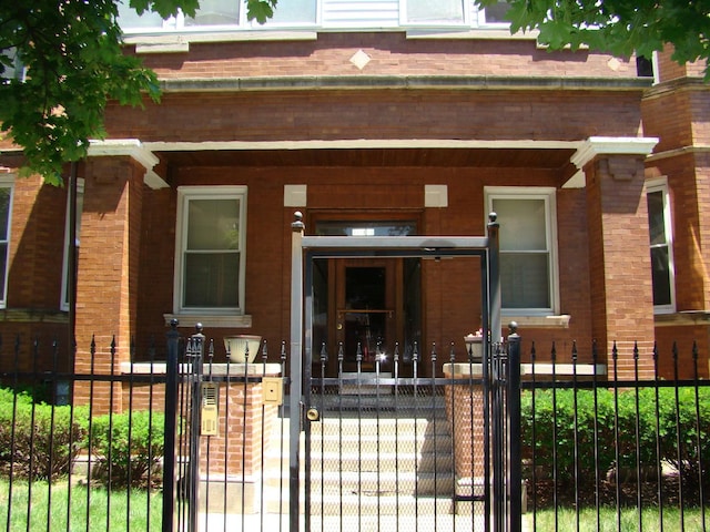 view of front of property with covered porch, brick siding, a fenced front yard, and a gate