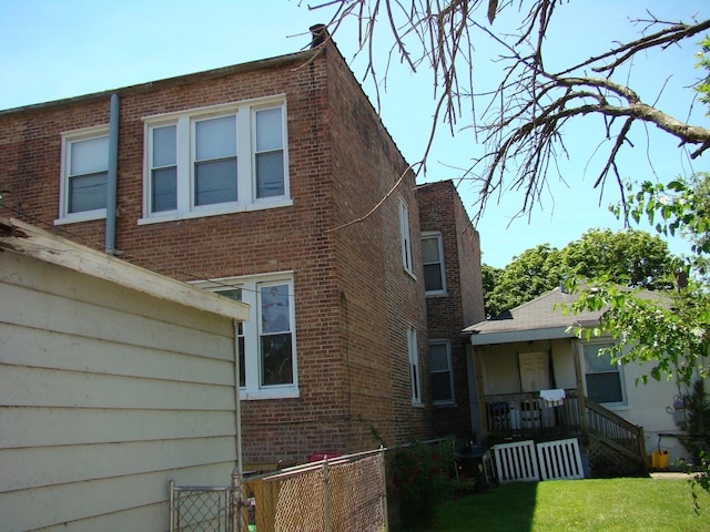 view of home's exterior featuring covered porch, brick siding, and a lawn