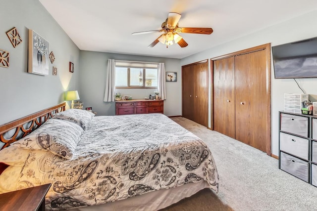 bedroom with carpet flooring, ceiling fan, and two closets