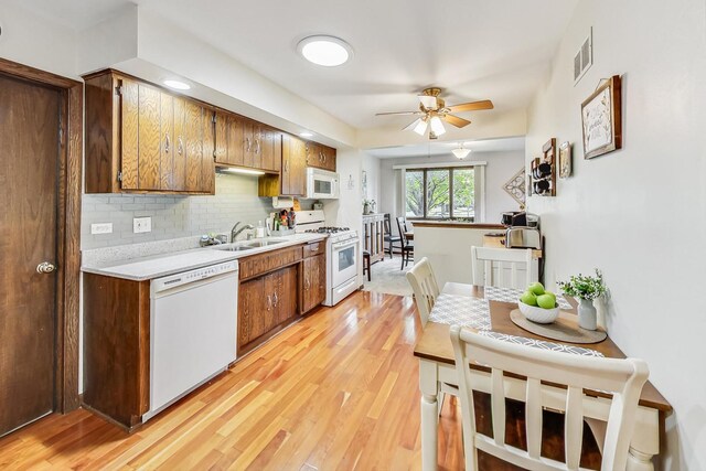 kitchen with white appliances, tasteful backsplash, sink, ceiling fan, and light hardwood / wood-style floors