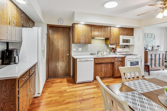 kitchen featuring backsplash, white appliances, light hardwood / wood-style floors, sink, and ceiling fan