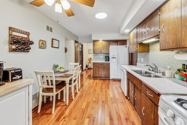 kitchen with white appliances, backsplash, sink, ceiling fan, and light hardwood / wood-style floors