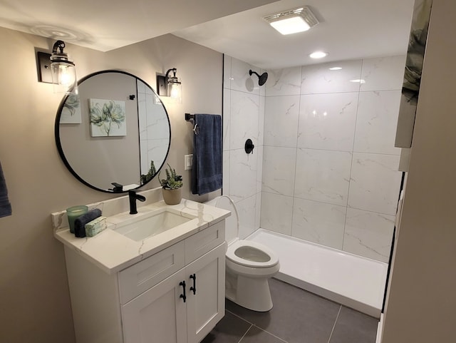 bathroom featuring vanity, toilet, tiled shower, and tile patterned flooring