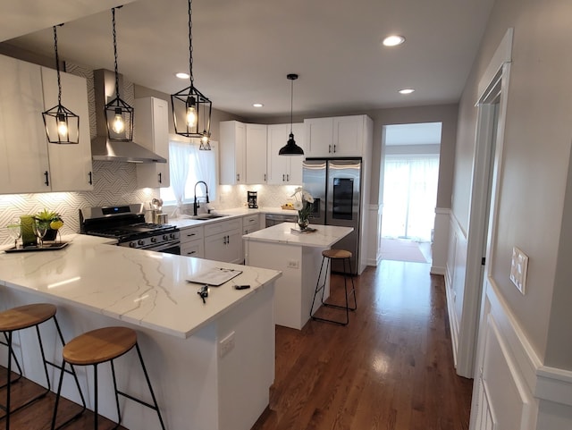 kitchen featuring a kitchen island, decorative light fixtures, a kitchen bar, stainless steel appliances, and sink