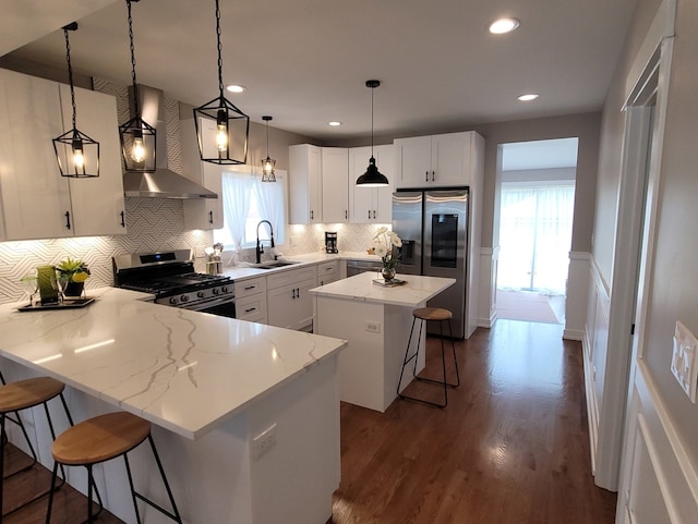 kitchen with stainless steel appliances, wall chimney range hood, pendant lighting, a kitchen bar, and a kitchen island