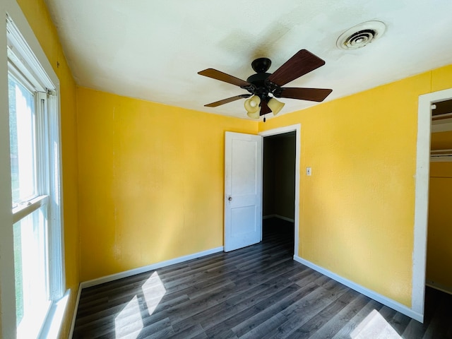 spare room featuring plenty of natural light, ceiling fan, and dark hardwood / wood-style floors