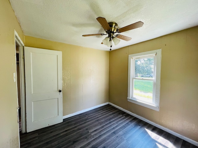 spare room featuring dark wood-type flooring, a textured ceiling, and ceiling fan