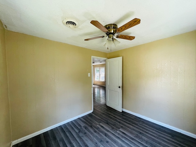 empty room with ceiling fan, dark hardwood / wood-style flooring, and a textured ceiling