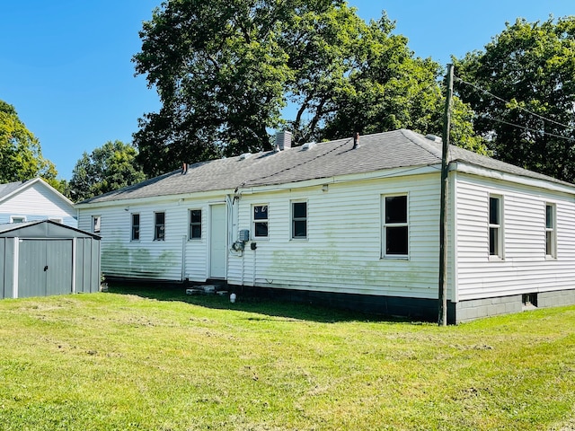 rear view of house with a yard and a storage unit